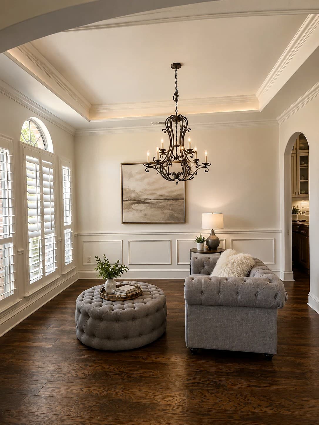 Finished interior by REVIBE REMODELING — freshly painted walls with crown molding, wainscoting, and trim, a tray ceiling, and dark hardwood floors.