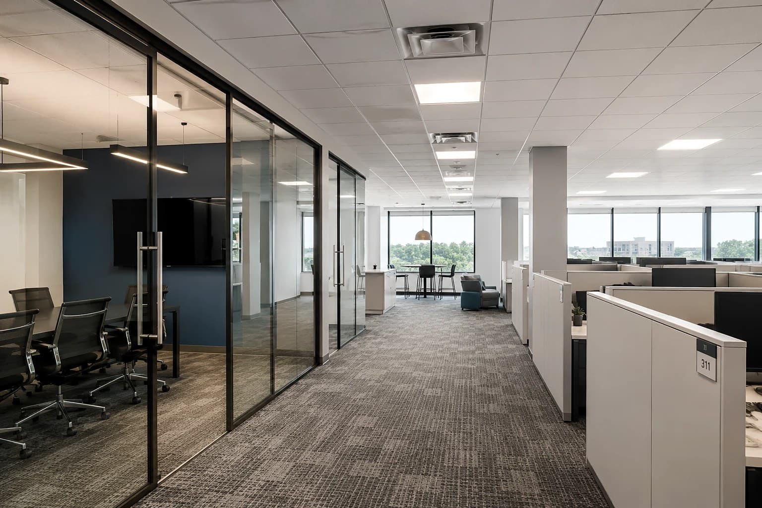Finished commercial office interior with a level suspended acoustic ceiling tile (ACT) grid and recessed lighting throughout, running above glass-fronted offices, an open cubicle area, and floor-to-ceiling windows.